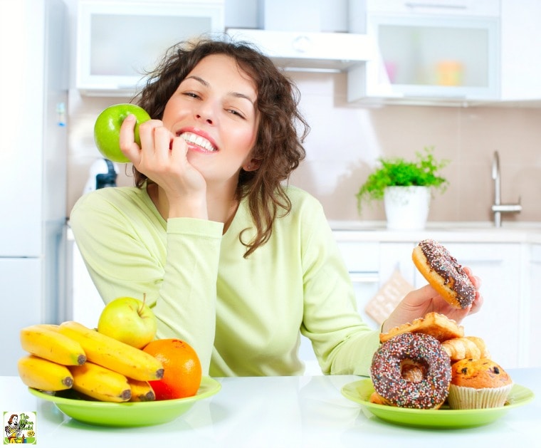 Young woman with healthy fruit and donuts and pastries in a white kitchen. 