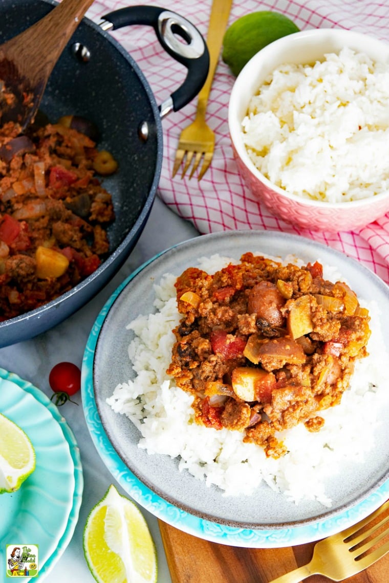 Overhead view of Mexican Picadillo served on rice, with bowl of rice, and picadillo in frying pan with wooden spoon.