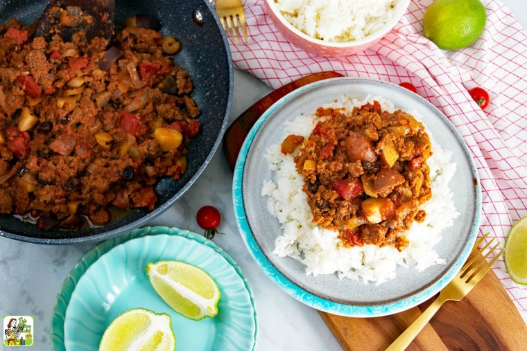 Mexican Picadillo served on ricewith picadillo in frying pan and sliced limes.