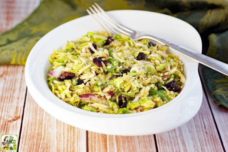 A white bowl of Brussel Sprouts Salad with Cranberries with fork and green napkin.
