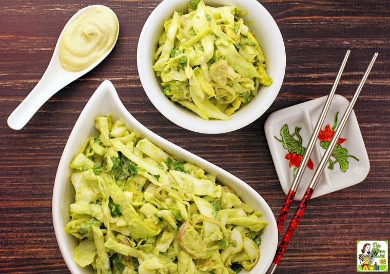 Bowls of Wasabi Coleslaw, a spoon of wasabi coleslaw dressing, and chopsticks.