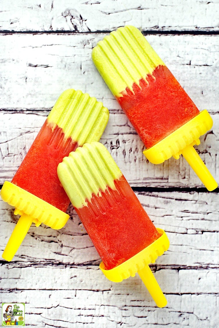 Avocado & Watermelon Ice Pops with yellow handles on a white wood tabletop.