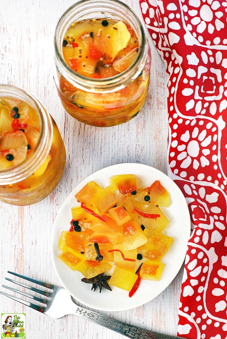 Overhead view of Mason jars and a plate of crisp watermelon pickles with red napkin and silver fork.