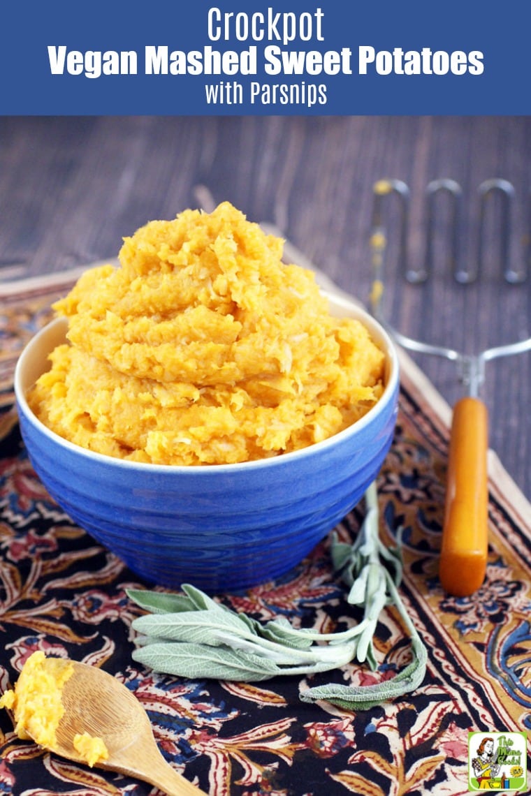 A blue bowl of Mashed Sweet Potatoes with an antique potato masher and wooden spoon.