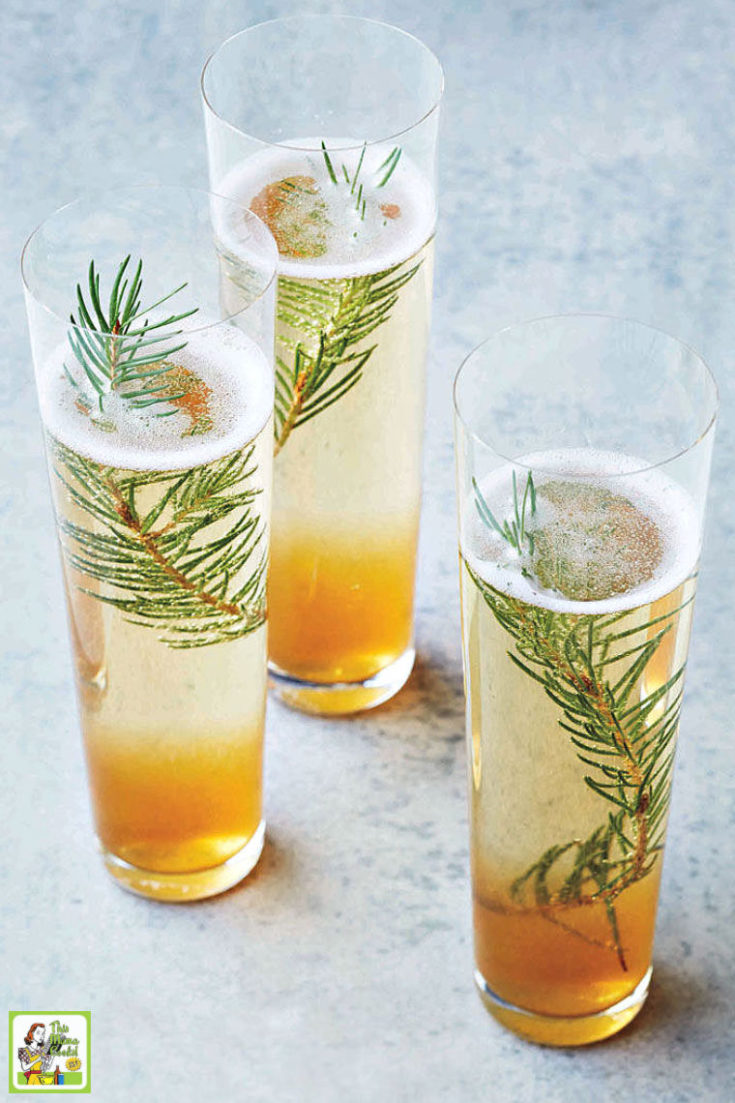 Three champagne cocktail glasses with pine sprigs.