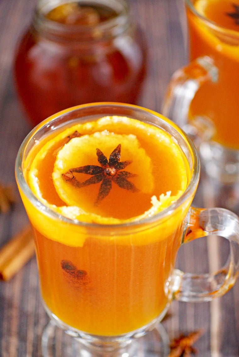 Closeup of a glass mug of hot toddy cocktail with orange peel and star anise.