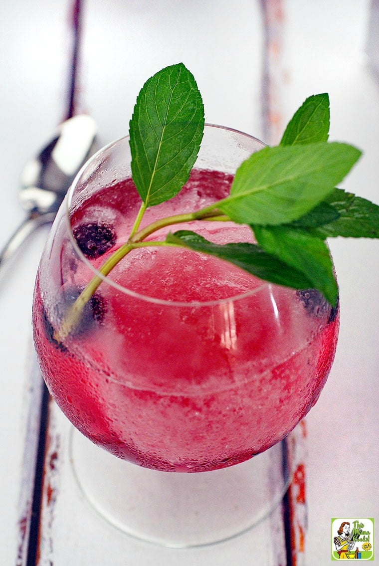 A frozen wine drinks with berry and mint garnish.
