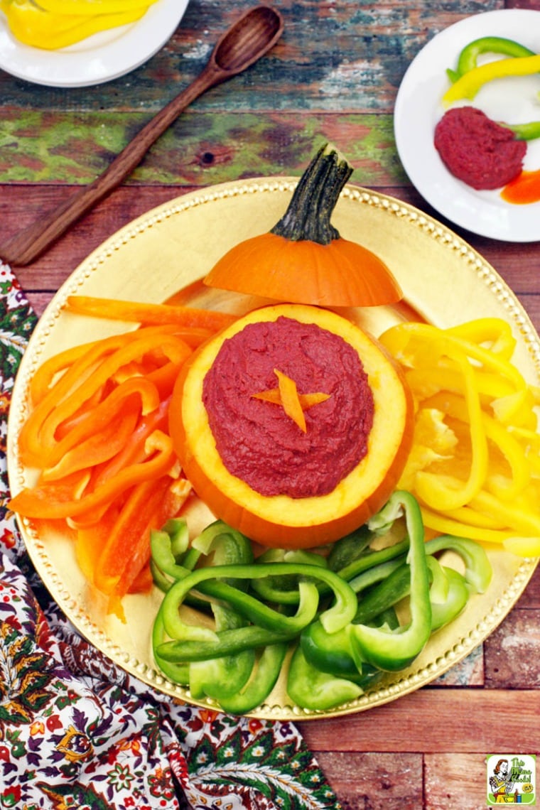 A serving plate of sliced peppers served with Cranberry Hummus in a small pumpkin.