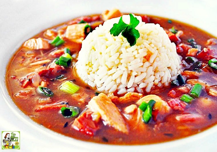 A bowl of chicken and sausage gumbo with a scoop of rice in the middle.