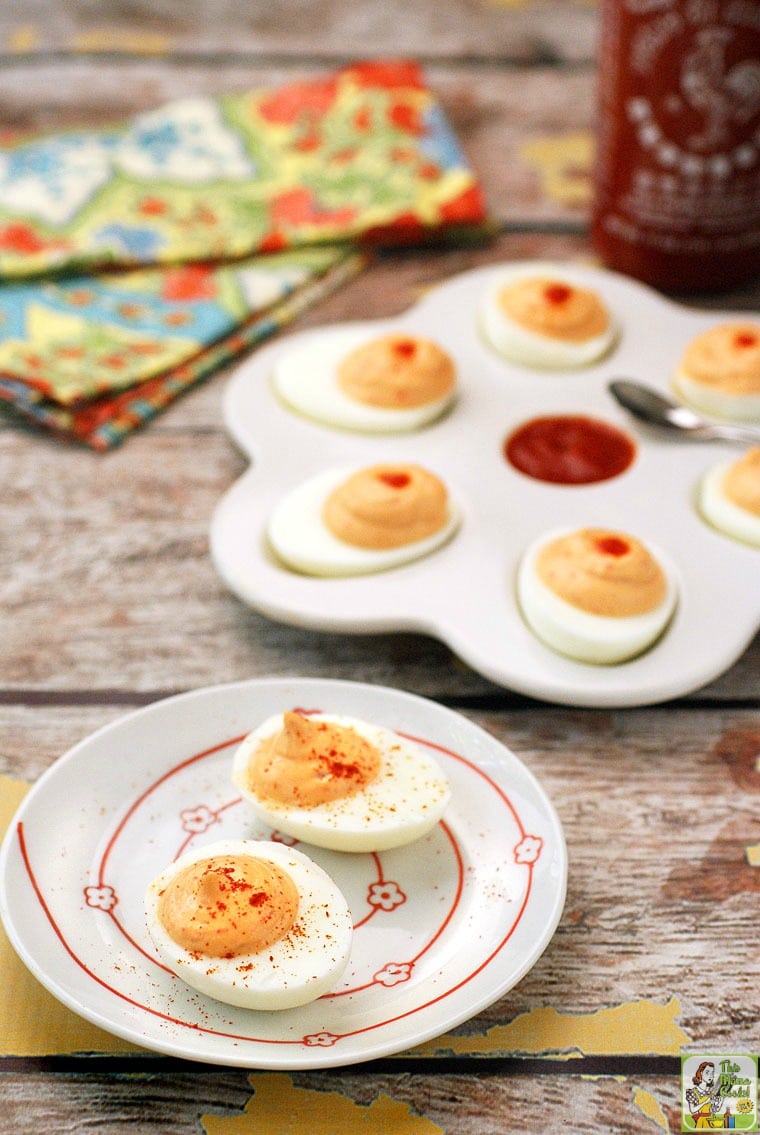 Two plates of spicy deviled eggs with sriracha dipping sauce.