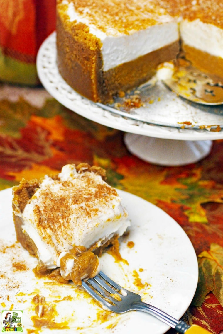 A white plate and fork with a slice of pumpkin pie on an autumn leaf placemat.