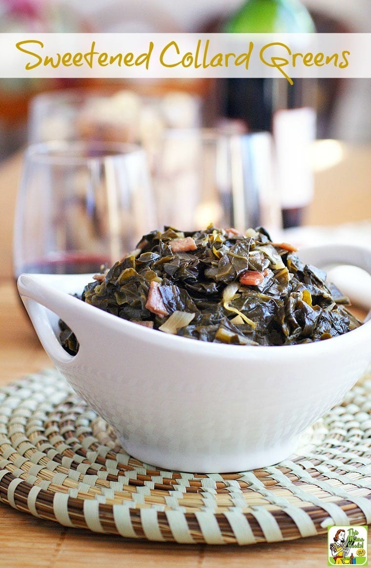 Closeup of a white bowl of sweet collard greens on a woven mat with wine glasses in the background.