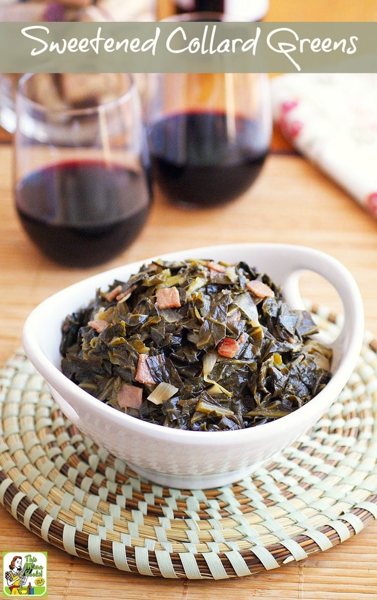 Overhead shot of a white bowl of sweet collard greens on a woven mat and red wine glasses.