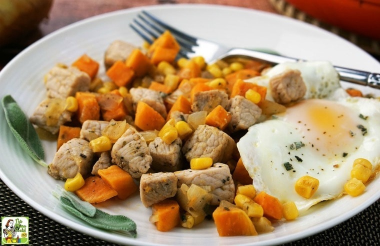 A white plate of Sweet Potato Pork Hash with egg and fork.