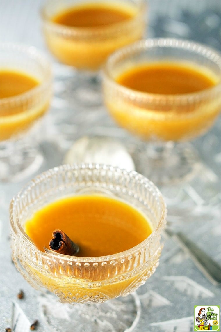 Three punch glasses of oranged spice tea with cinnamon sticks.