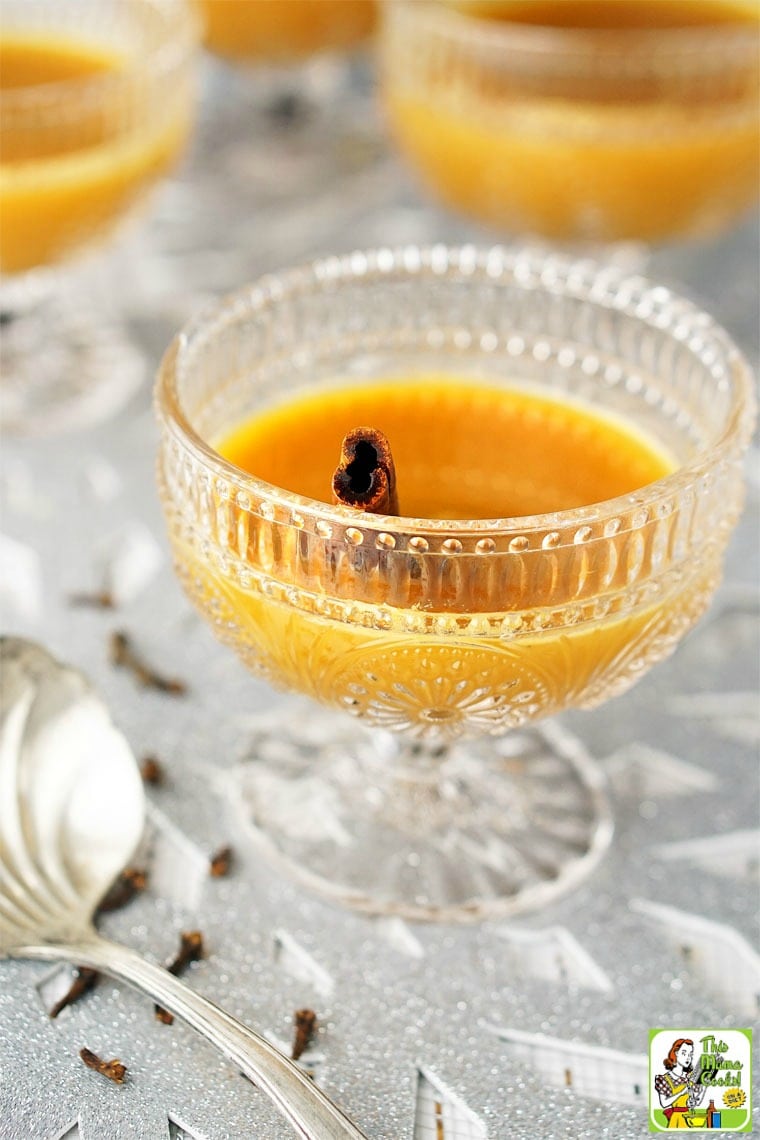 A glass of spiced orange tea with cinnamon sticks and silver serving ladle.