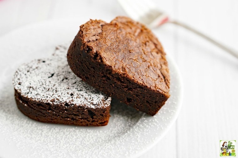 Two heart shaped Gluten Free Brownies on a plate with powdered sugar.