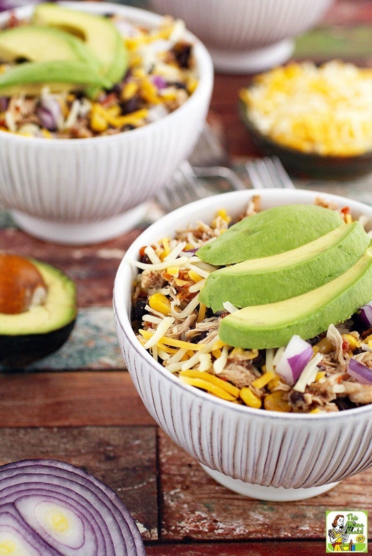 White bowls of Mexican Shredded Chicken Recipe with Black Beans & Corn with slices of avocado and diced onion