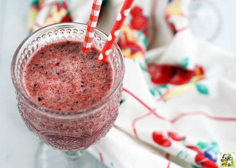 A glass of iced tea and berry smoothie with red paper straws and a vintage tablecloth.