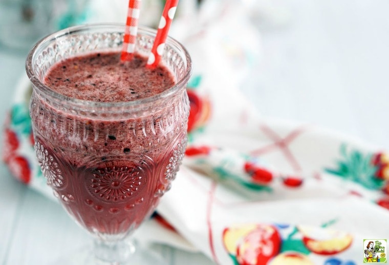 A glass of ice tea berry smoothie with red straws.