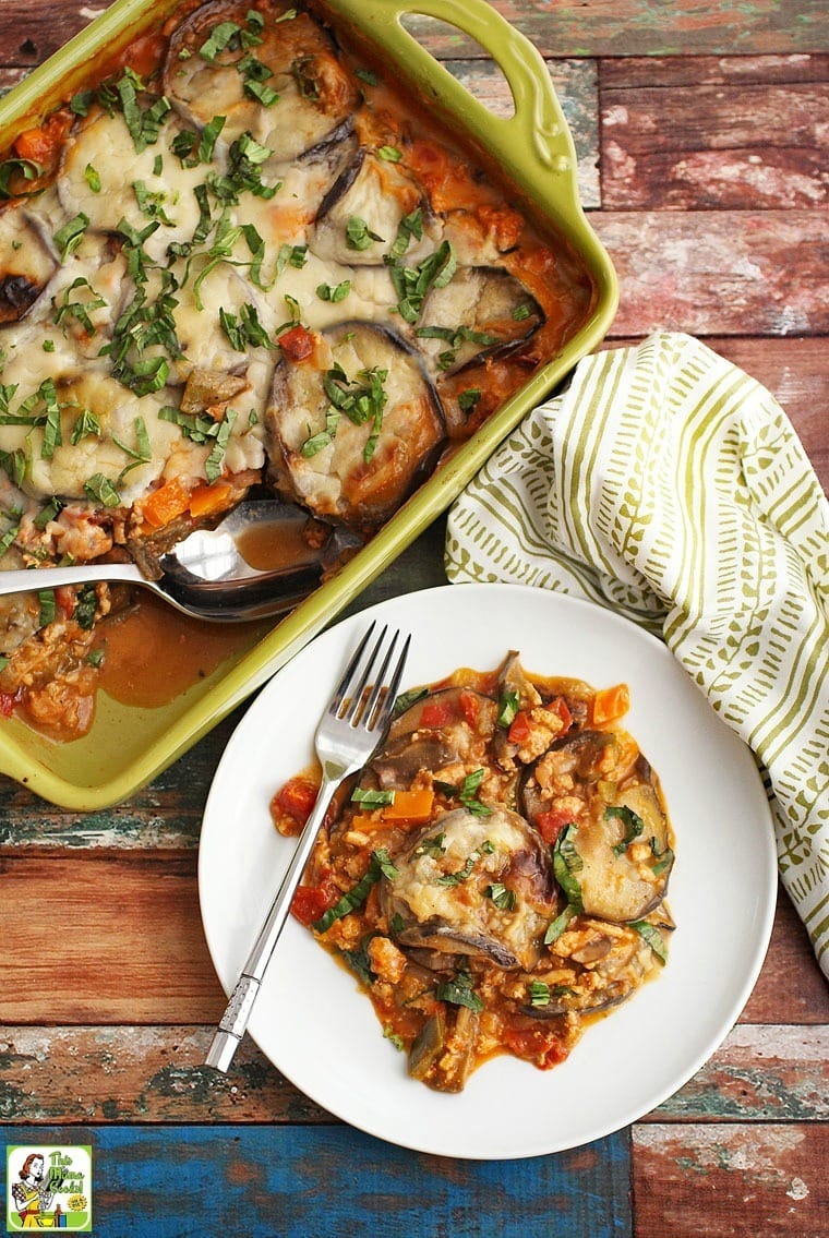 Overhead view of a plate and casserole of moussaka with gluten free Bechamel sauce with a napkin.