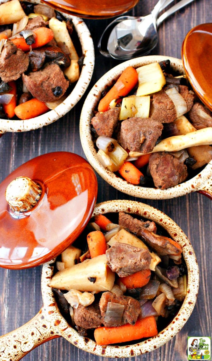 Closeup overhead view of three bowls of venison deer stew filled with root vegetables with lids and spoons.