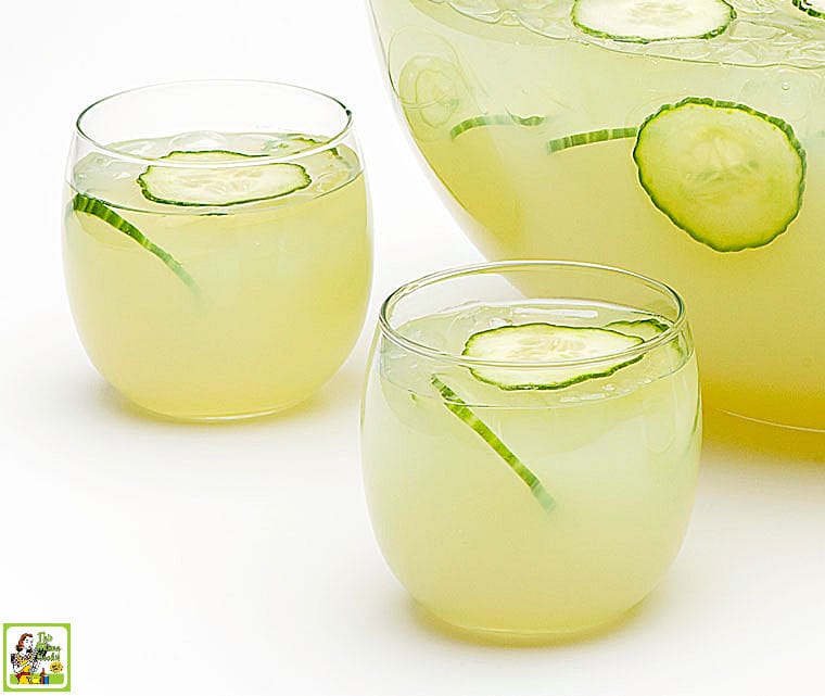 Two cocktail glasses of Sparkling Green Sangria with sliced cucumbers and grapes.