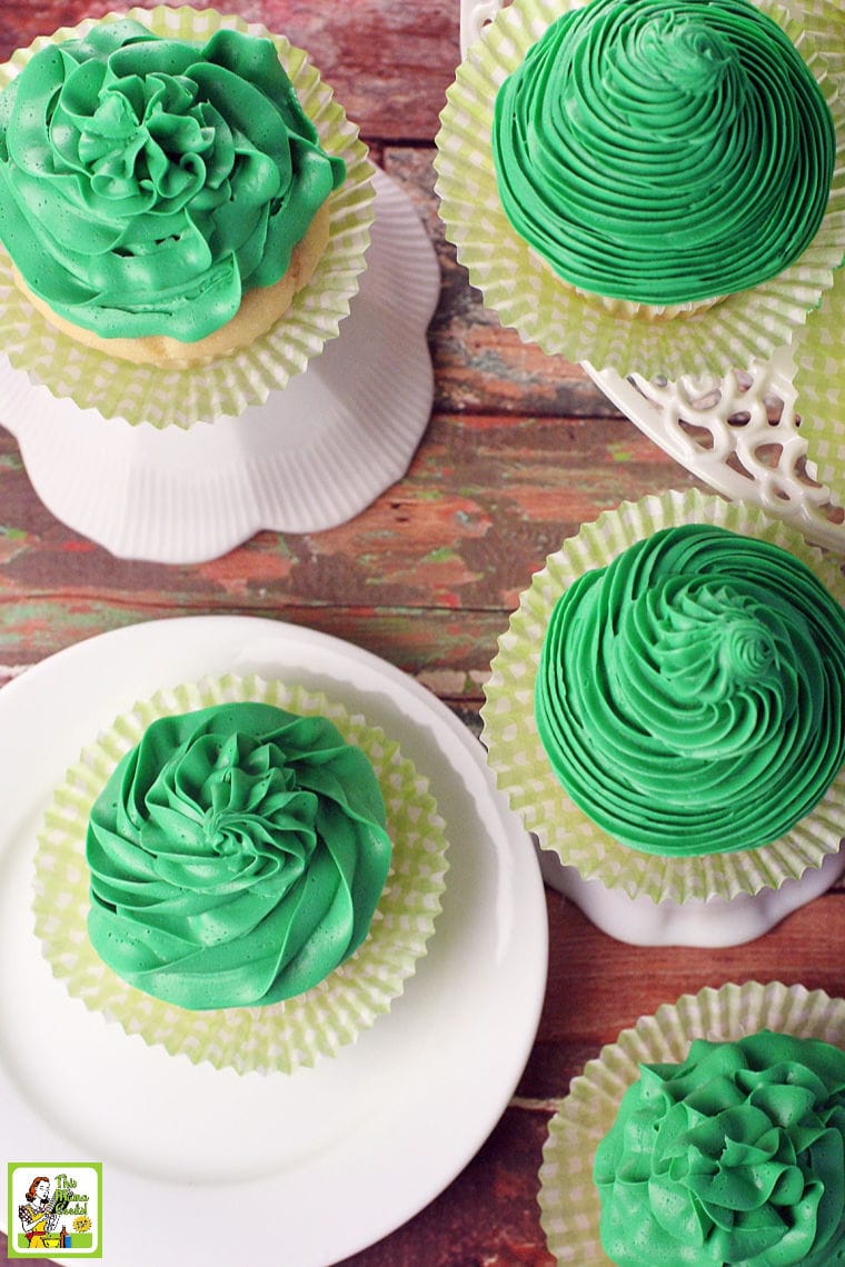 Overhead shot of cupcakes with green frosting with yellow cupcake paper cups on white cake stands. 