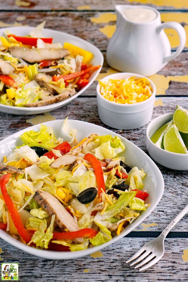 Two bowls of Chicken Fajita Salad with a pitcher of salad dressing.