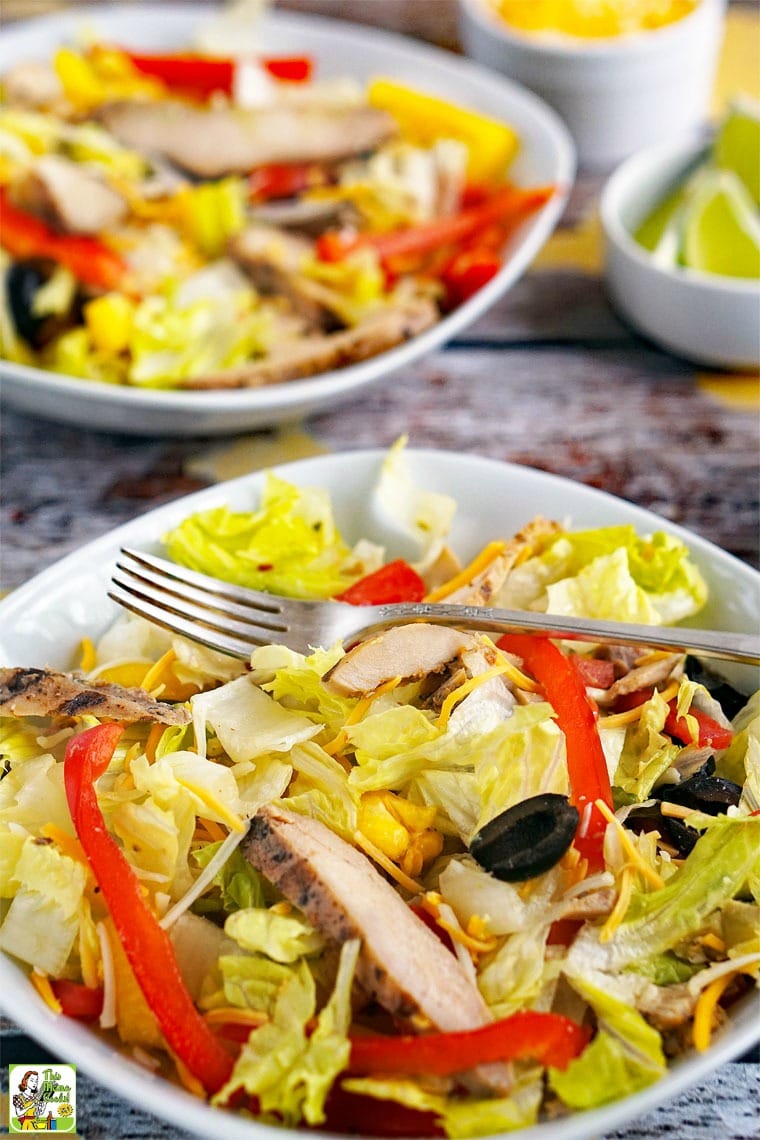 White bowls of chicken salad with red peppers and black olives.