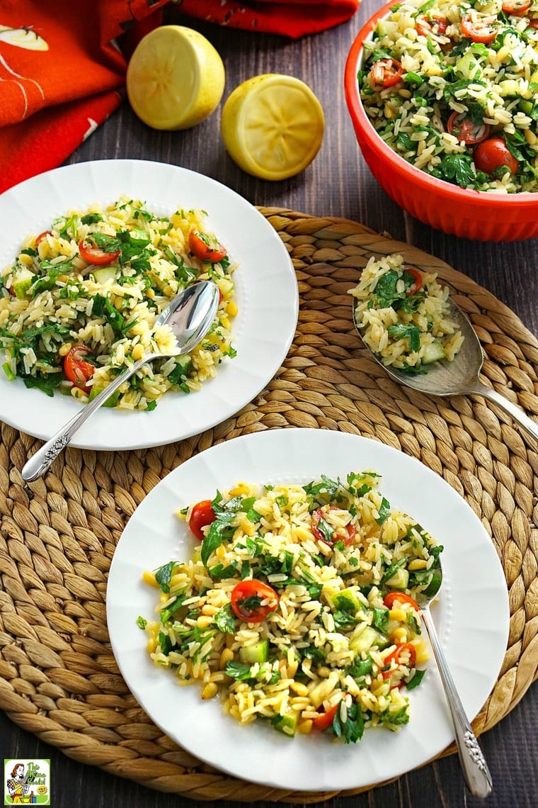 Plates of tabbouleh rice with tomatoes and parsley spoons on a woven straw mat.