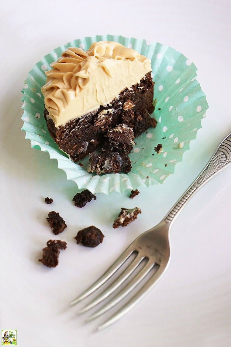 A closeup of a Chocolate Cupcake with Dulce de Leche Frosting with a colorful cupcake liner and an antique silver fork.