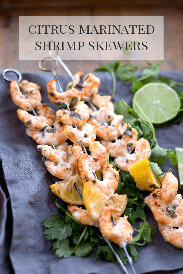Citrus Marinated Shrimp Skewers on a napkin with herbs and lemon wedges.