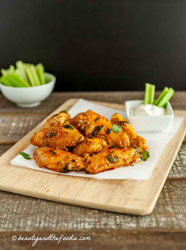Pile of Saucy Baked Buffalo Chicken Wings on a wooden board.