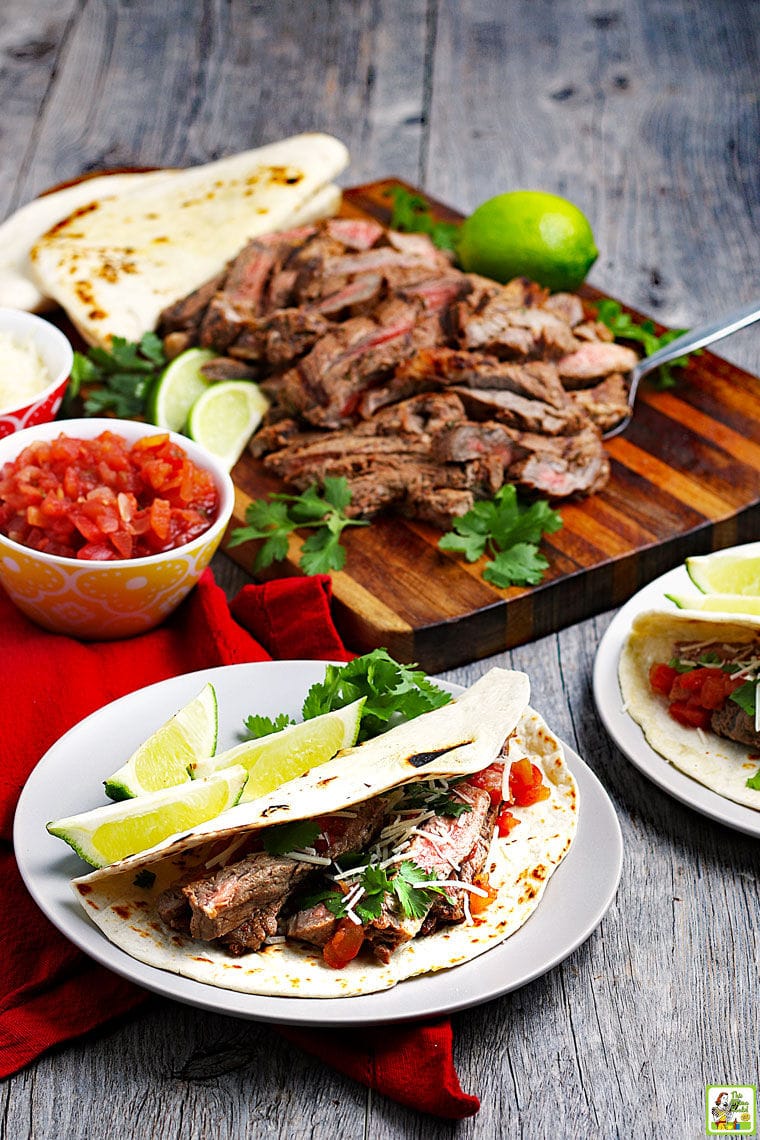 Carne asada tacos and carne asada meat on a wooden board with salsa.