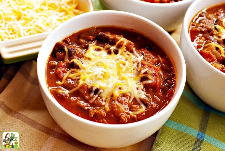 Bowl of turkey pumpkin chili with beans and shredded cheddar cheese.