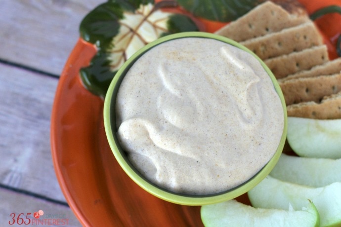 Healthy pumpkin pie dip with cracker and apple slices on an orange plate.