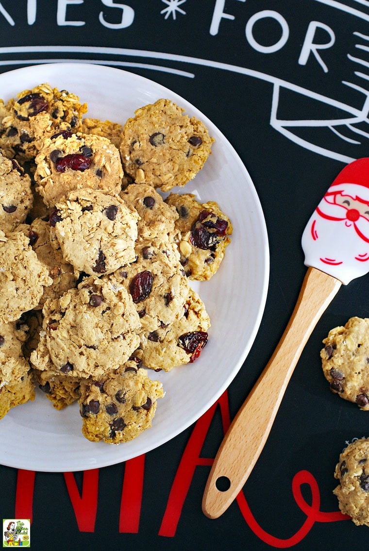 Cookies for Santa placemat with a plate of gluten free oatmeal cookies with chocolate chips and raisins and a Santa spatula.