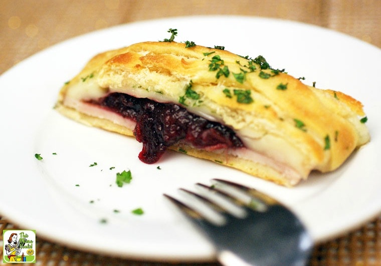 A slice of turkey cranberry crescent braid served on a white plate with a silver fork.