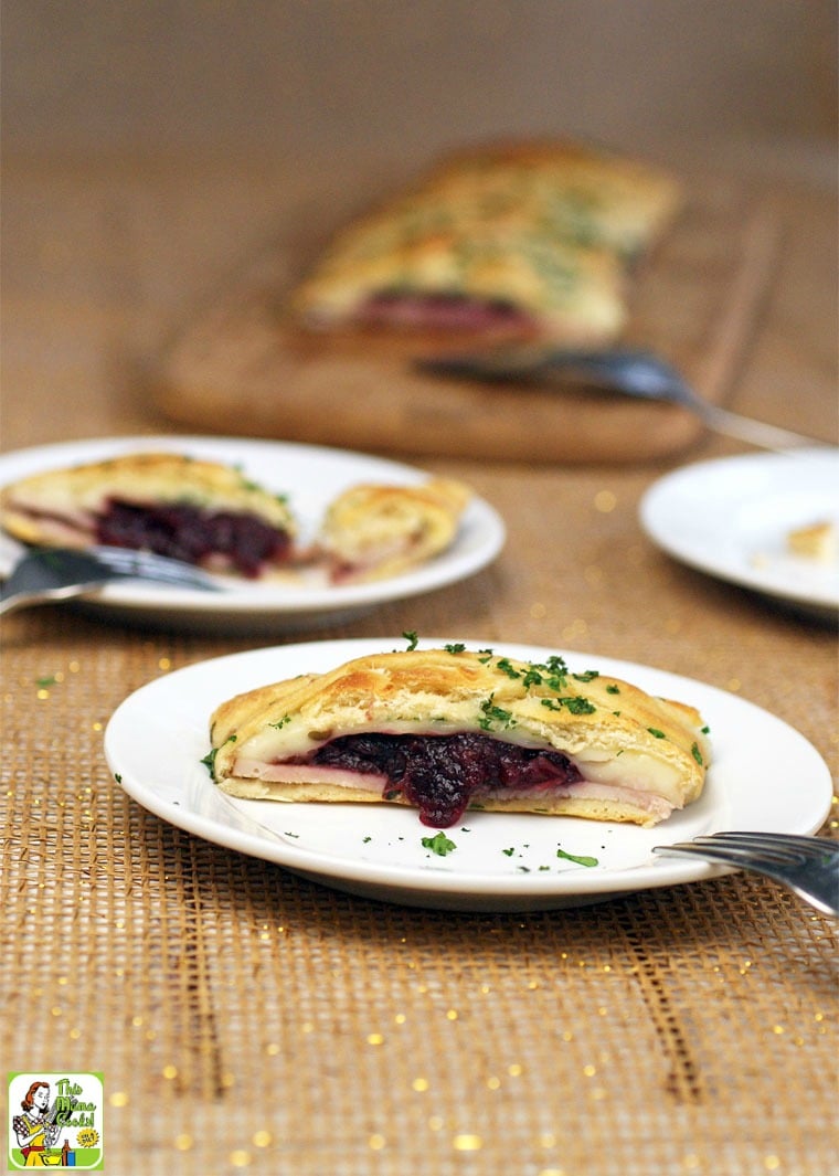 Slices of crescent braid with turkey and cranberry appetizers served on white plates.