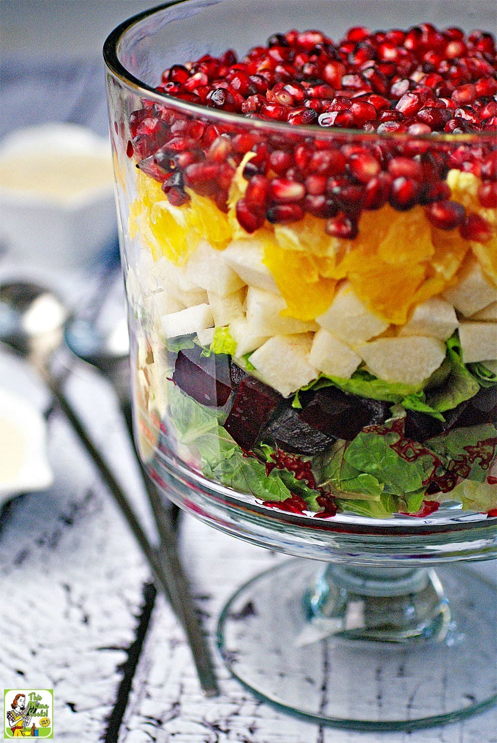 Closeup of a Mexican Christmas Eve Salad in a glass bowl with layers of lettuce, beets, jicama, oranges, and pomegranate seeds.