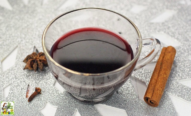 A glass of Slow Cooker Smoking Bishop with spices on a metallic placemat.