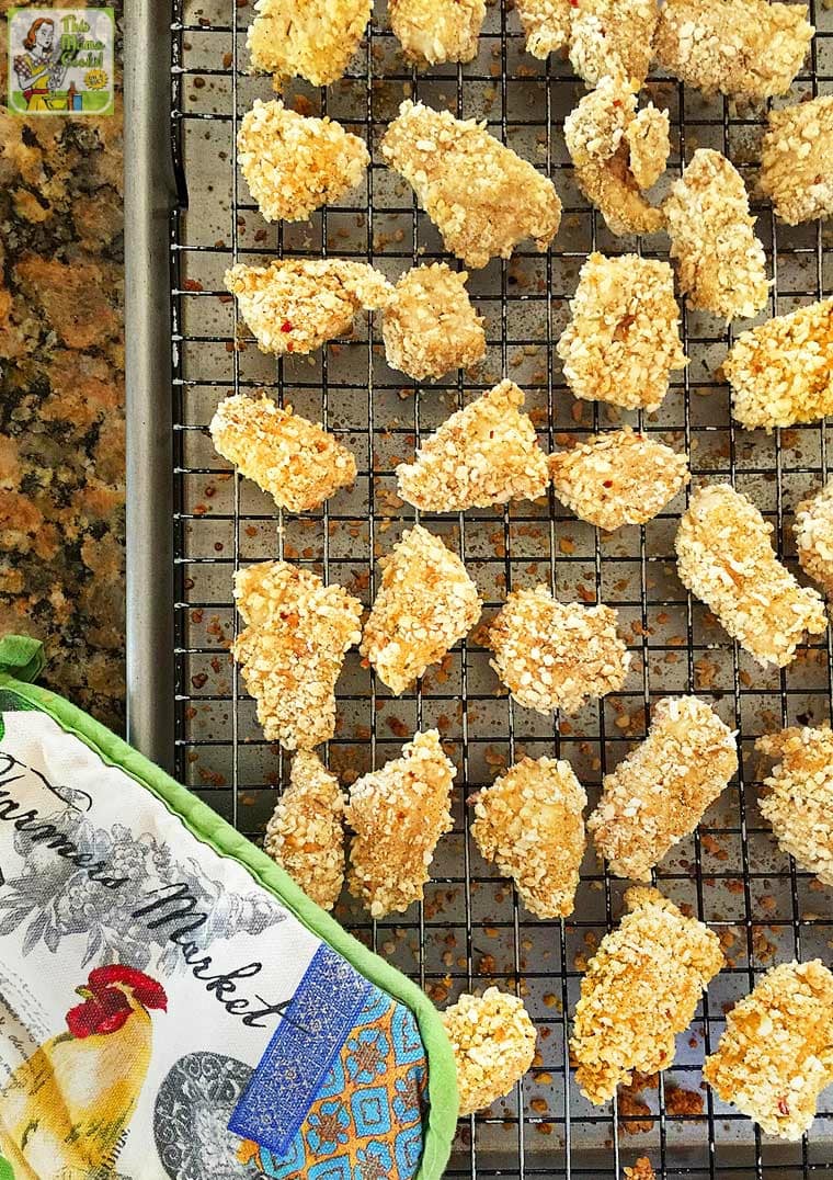 A baking tray of Chicken Nuggets with oven mitt.