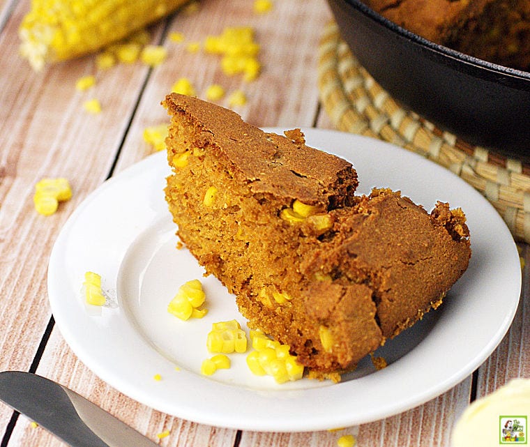 A piece of gluten free cornbread on a white plate with kernels of corn.