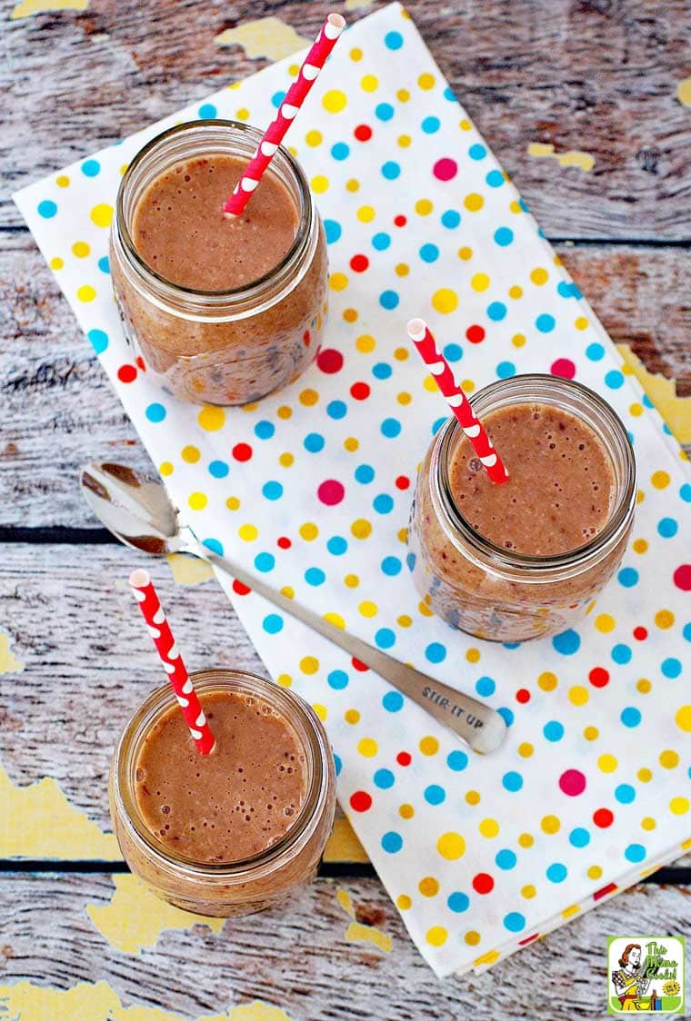 Oatmeal smoothies in mason jars with red straws on a polka dot tea towel. 