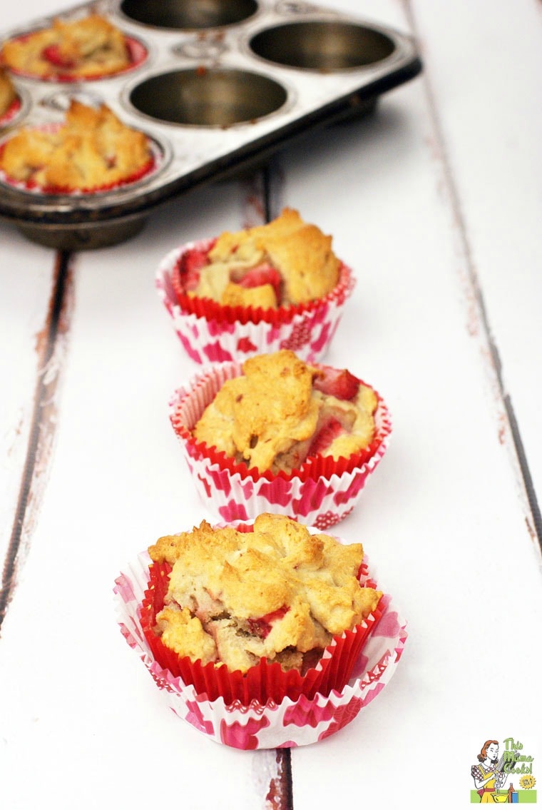 Muffin baking pan and three strawberry muffins in decorative cupcake liners.