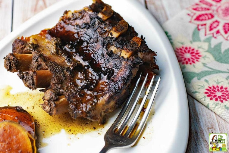 Crock-Pot Ribs and sweet potato with fork on white plate with floral napkin.