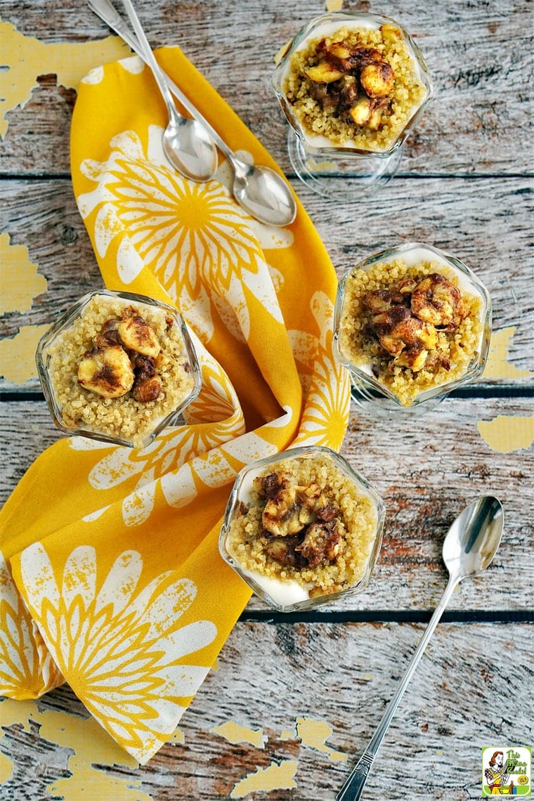 Dish of Fruit and Yogurt Parfait with Quinoa on a yellow dish towel and spoons.