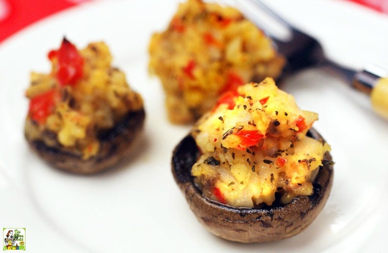 Three gluten free stuffed mushrooms on a white plate with a fork.
