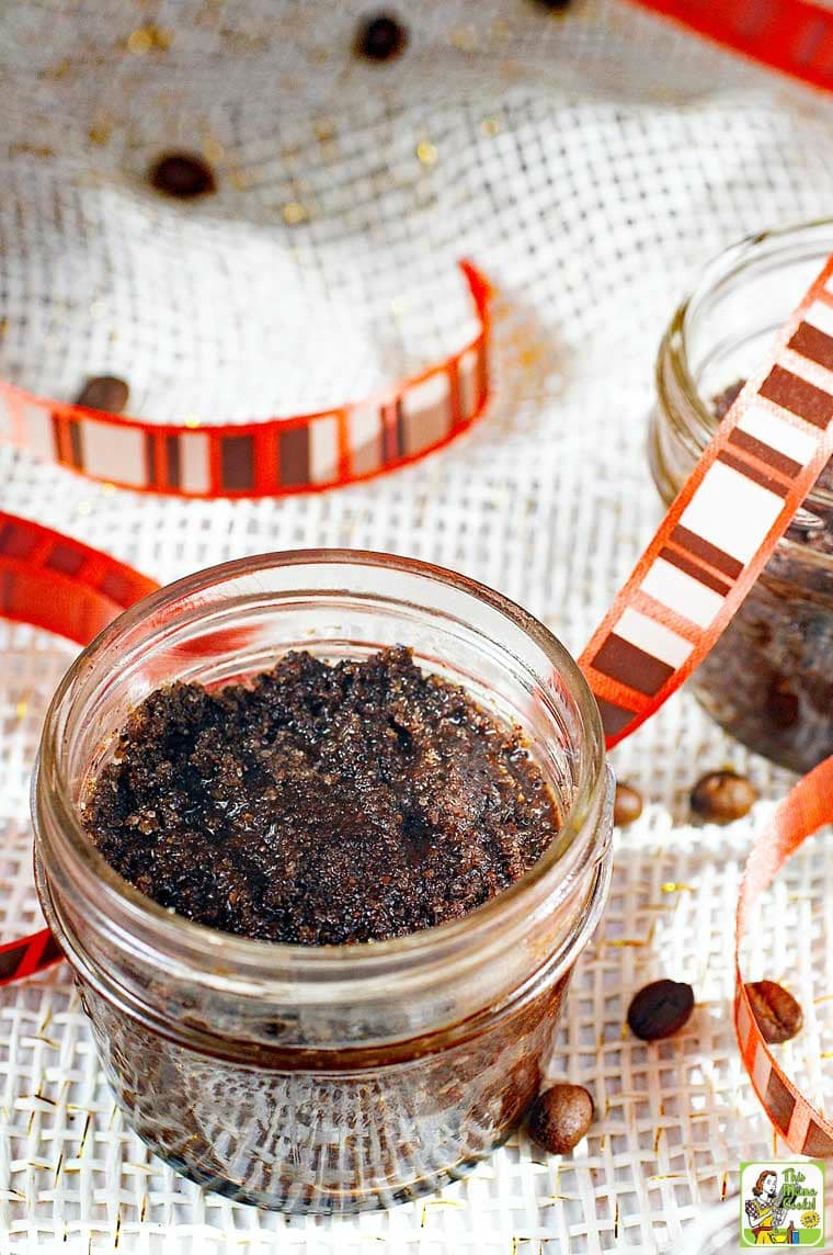 A small jar of coffee sugar scrub with coffee beans and striped ribbon. 